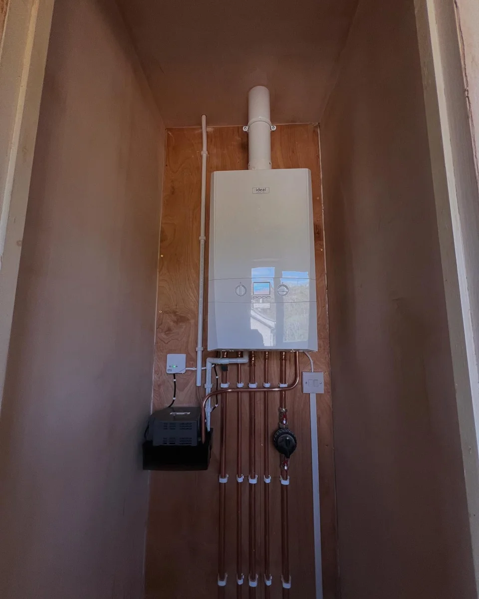 Wall-mounted Ideal boiler with a vertical flue and neatly arranged exposed copper pipework